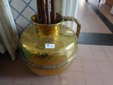 a gold vase with sticks in it sitting on the floor