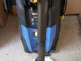 a blue and black vacuum on the floor next to a cardboard box