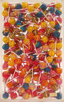 colorful lollipops in a clear box on a white surface
