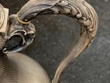an antique silver plated pitcher with a handle on a table