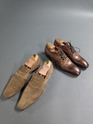 two pairs of brown shoes sitting on top of a gray surface