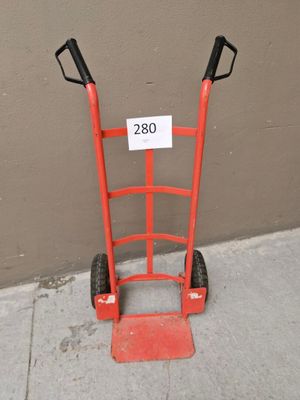 un diable rouge sur lequel est accrochée une pancarte