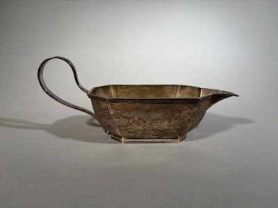 un pot à lait ancien plaqué argent, muni d'une anse, sur un fond blanc
