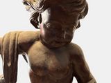statue of a little boy sitting on the ground with his hands on his knees