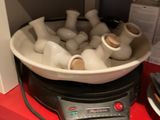 un bol rempli de vases blancs posé sur une étagère rouge