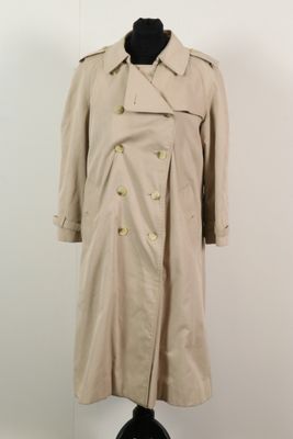 un trench-coat posé sur un pied de mannequin dans une pièce blanche