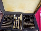 des couverts dans un coffret posé sur une table recouverte d'une nappe rose