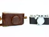 two cameras sitting next to each other on a white surface