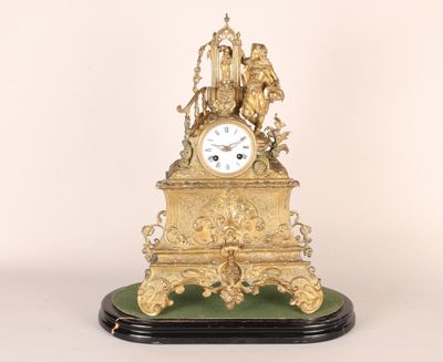 une horloge dorée posée sur un socle vert
