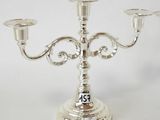 silver plated candelabra with two candles on top of it