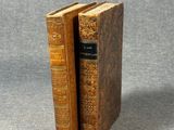 two old books sitting on top of each other on a table