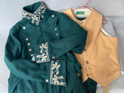 a green jacket and a tan vest on a bed