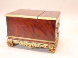 a small wooden box with a gold decoration on it