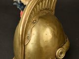a teddy bear sitting on top of a gold helmet