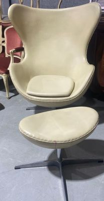 une image représentant une chaise et un pouf dans une pièce où se trouvent plusieurs chaises