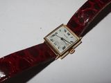a red strap around a watch on a white surface