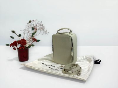 a small bag sitting on a table next to a vase