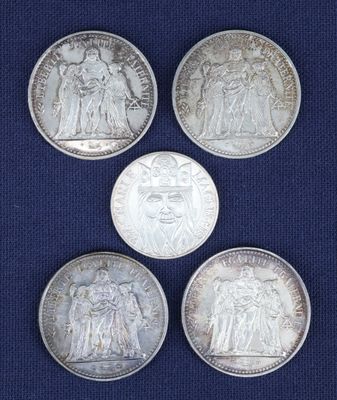 quatre pièces d'argent de tailles et de formes différentes sur un fond bleu