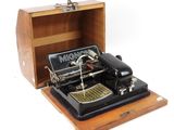 une machine à coudre à l'ancienne dans une boîte en bois posée sur une surface blanche