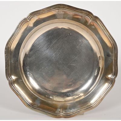 silver plate with scalloped edge on a stand on a white background