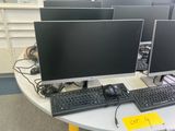 several computer monitors and keyboards on a table in a room