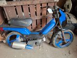 une moto bleue garée dans un garage, à côté d'une caisse en bois