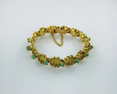 a gold bracelet with green stones