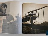 an open book with a picture of a man standing next to a plane