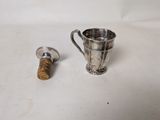 a silver cup and a cork stopper on a white surface