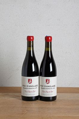 two bottles of red wine sitting on top of a wooden table