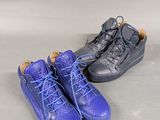 two pairs of blue and black shoes sitting on top of a white surface
