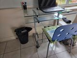 a glass desk with a laptop on it and a chair in front of it