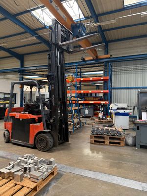 a forklift in a warehouse with a lot of pallets on the floor