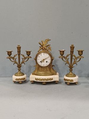 trois bougies et une horloge posées sur une table