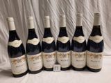 six bouteilles de vin sont alignées sur une table