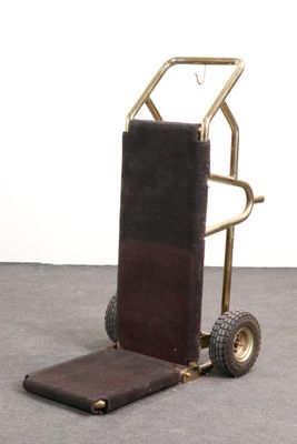 a small hand truck with a luggage bag on the back