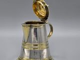 an antique silver and gold coffee pot with a lid on a white surface