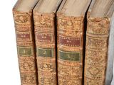 several old books are stacked on top of each other on a white surface