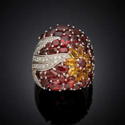 an image of a ring with garnets and diamonds on a black surface