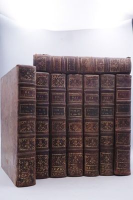 Plusieurs vieux livres sont empilés les uns sur les autres devant un fond blanc.