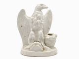 une statue blanche représentant un oiseau tenant une tasse dans son bec