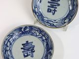 two blue and white plates with chinese writing on them on a white surface