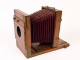 an old wooden camera that is sitting on a white surface