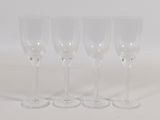 four empty wine glasses lined up on a white surface