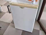 a small white refrigerator in the corner of a room