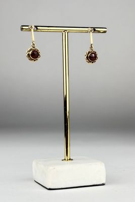 une paire de boucles d'oreilles en or et en garnétite, présentées sur un support