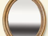 un miroir ovale avec un cadre doré accroché à un mur blanc