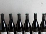 six bottles of wine are lined up on a wooden table