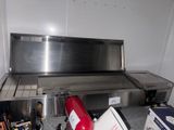 a large stainless steel grill with a red fire extinguisher next to it