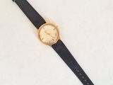 gros plan d'une montre sur une surface blanche avec un bracelet noir